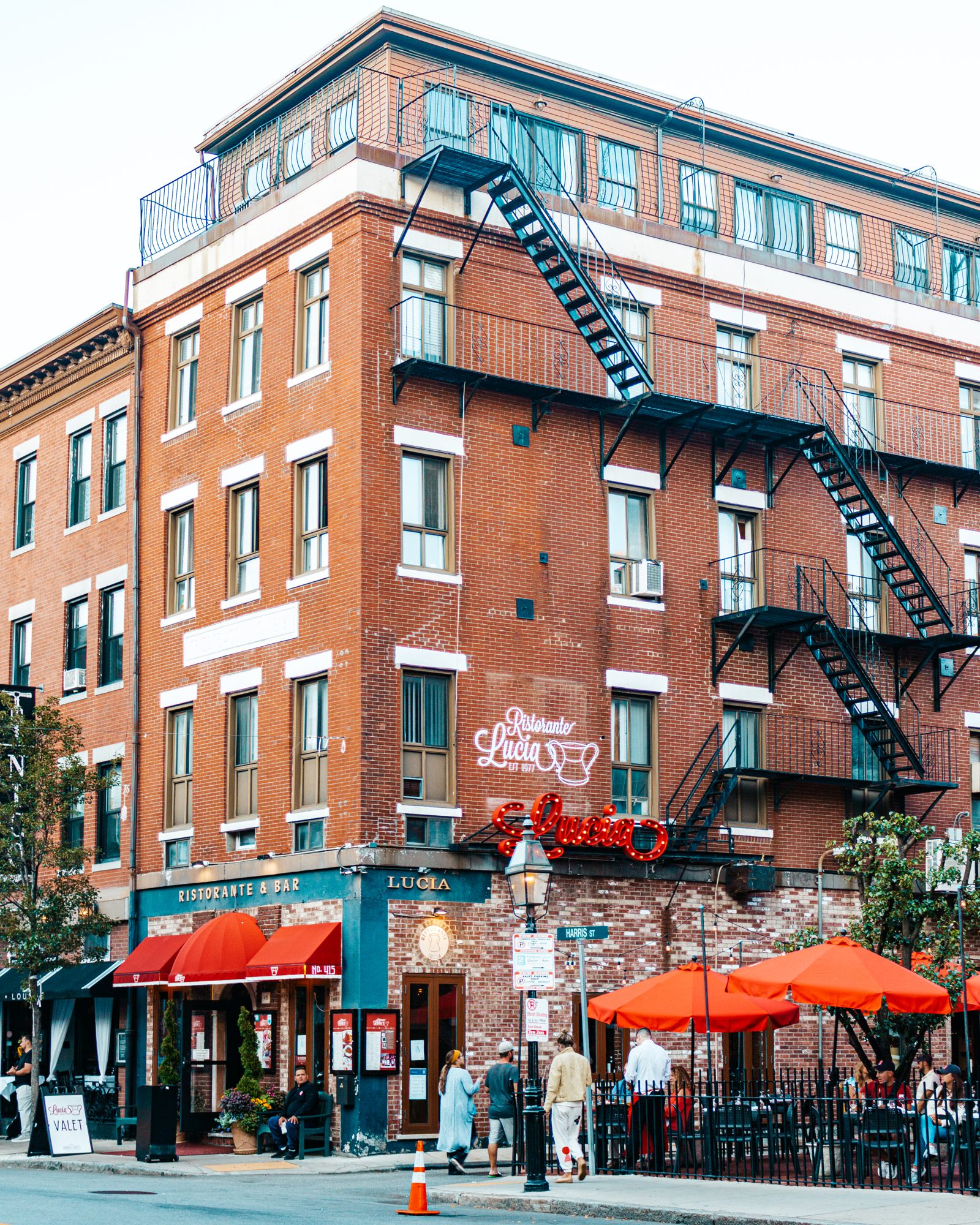 Red-brick corner building with fire escapes and terraces