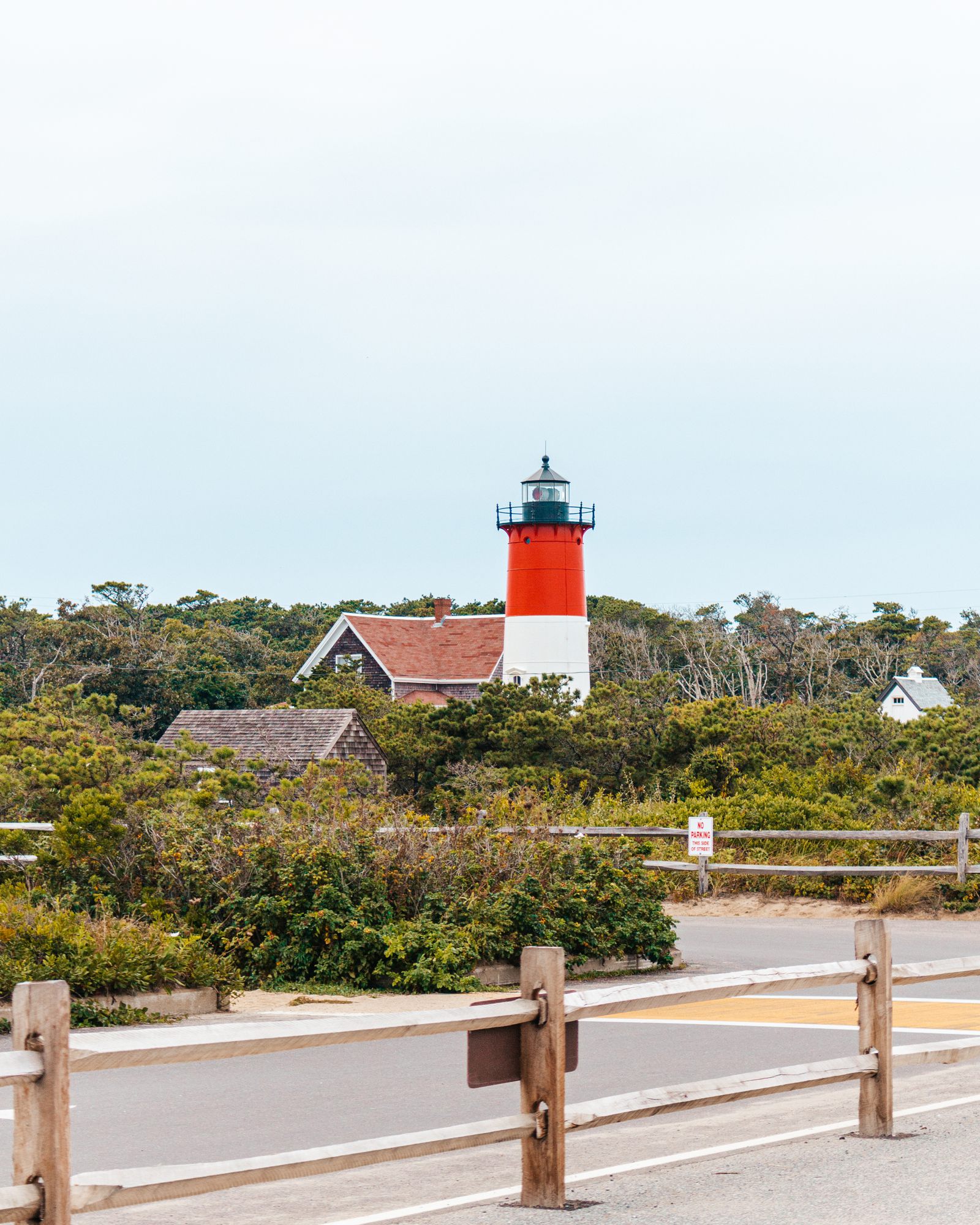 Red-and-white lighthouse behind a wooden fence