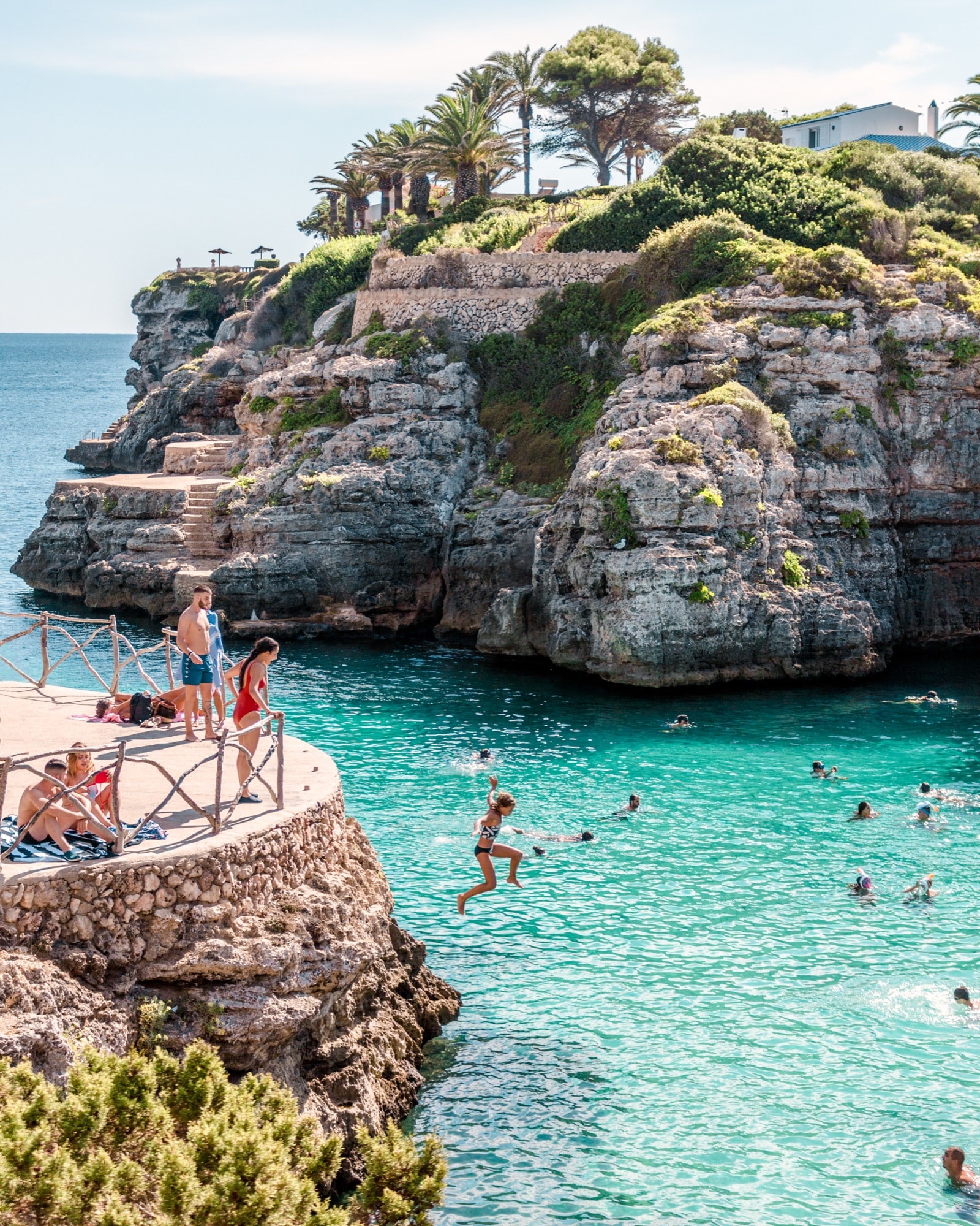 Swimmers jumping into a turquoise cove